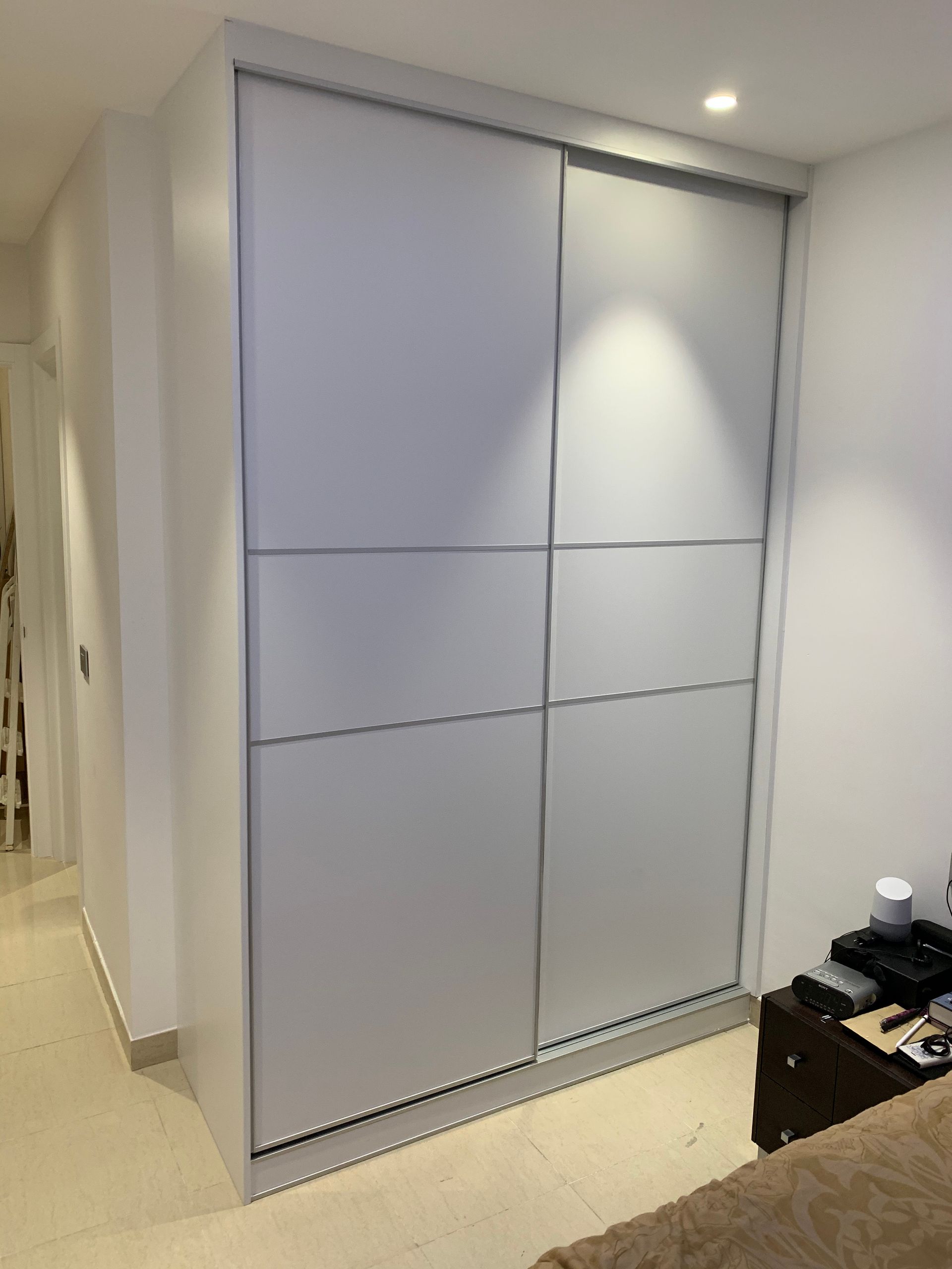 Un dormitorio con un armario con puertas correderas y una cama.