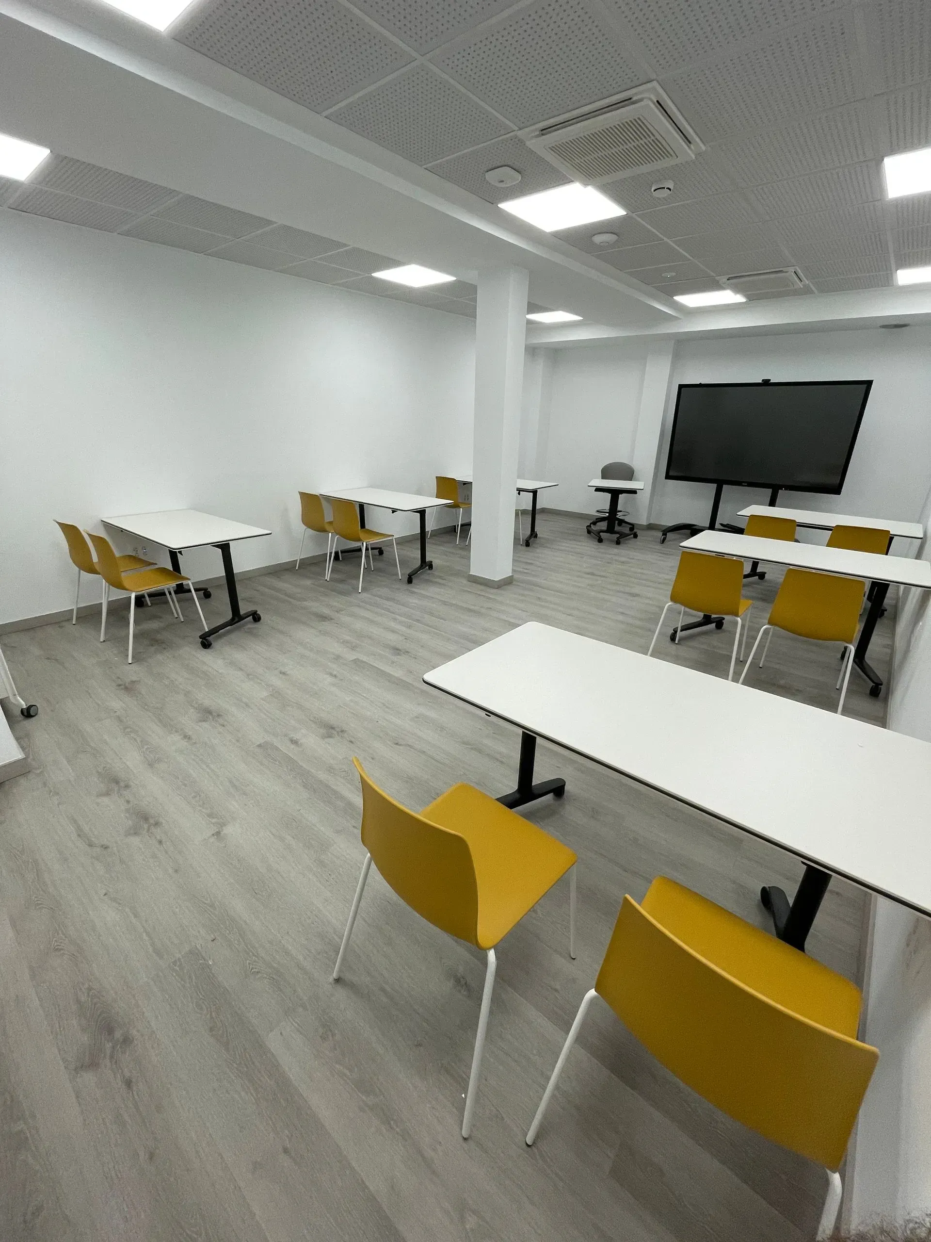 Una sala con mesas y sillas y un televisor de pantalla plana.