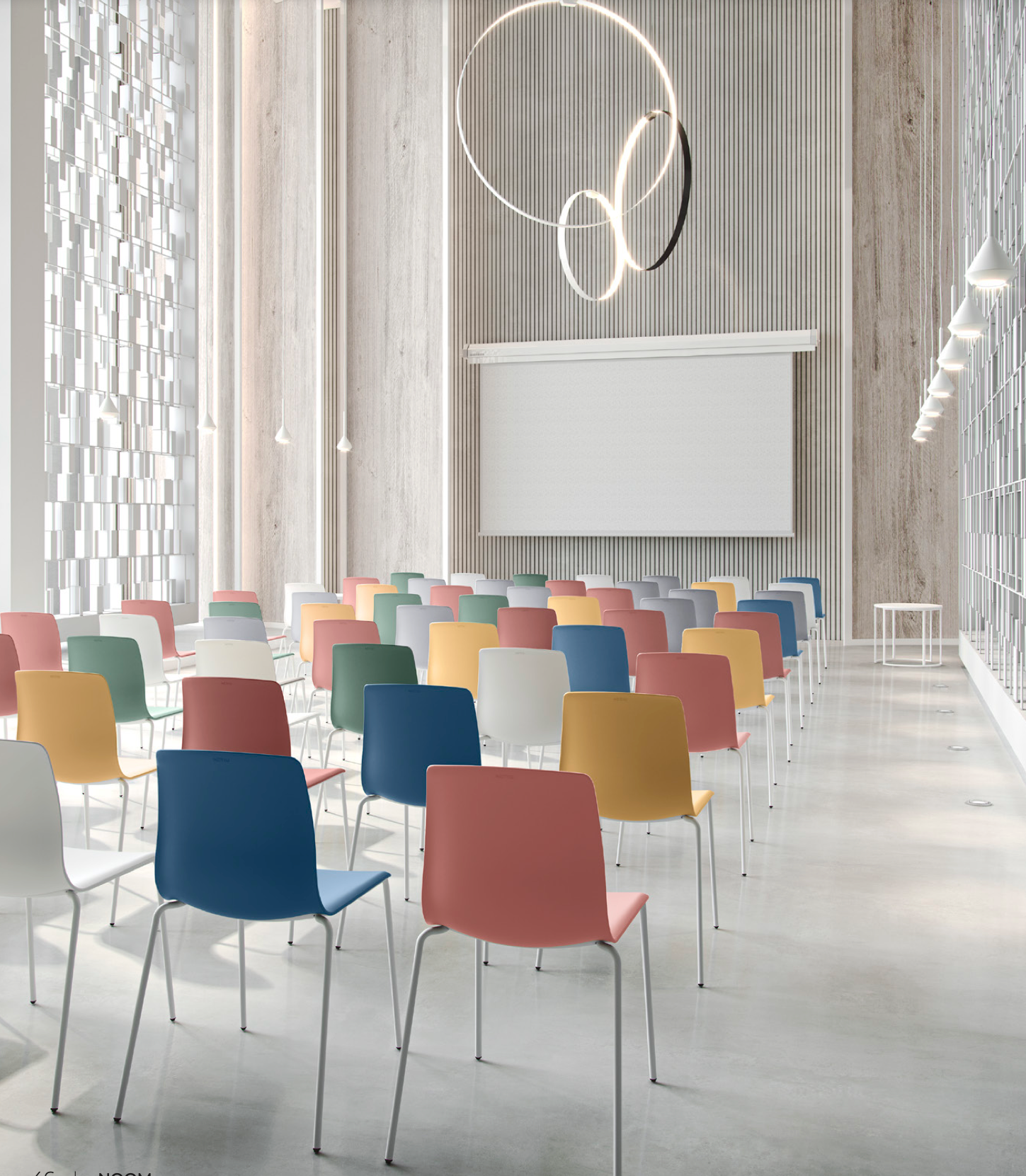 Una sala con filas de sillas de colores y una pantalla de proyección.