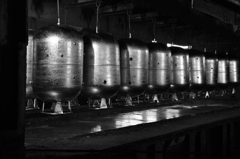 Ein Schwarz-Weiß-Foto einer Reihe von Metalltanks in einer Fabrik | SferaTec Gebäudetechnik