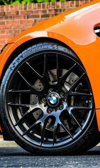 Eine Nahaufnahme eines orangefarbenen BMW mit schwarzen Rädern