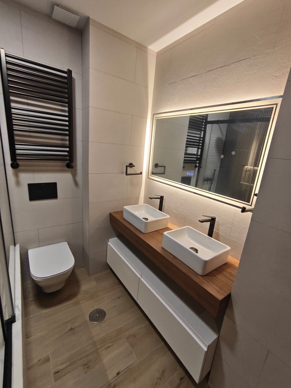 Un baño con un gran espejo y un toallero.