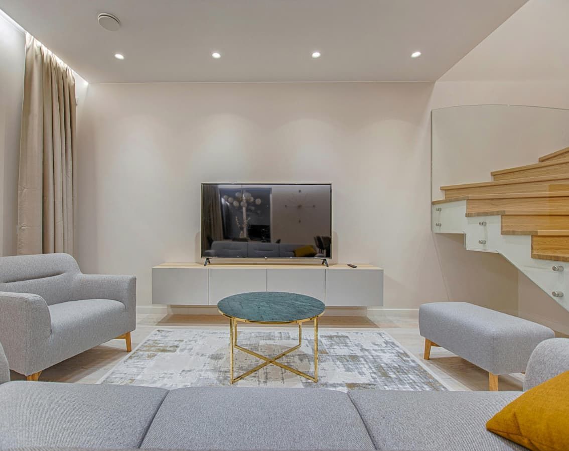 Una sala de estar con sofá, sillas, mesa de café y televisión.