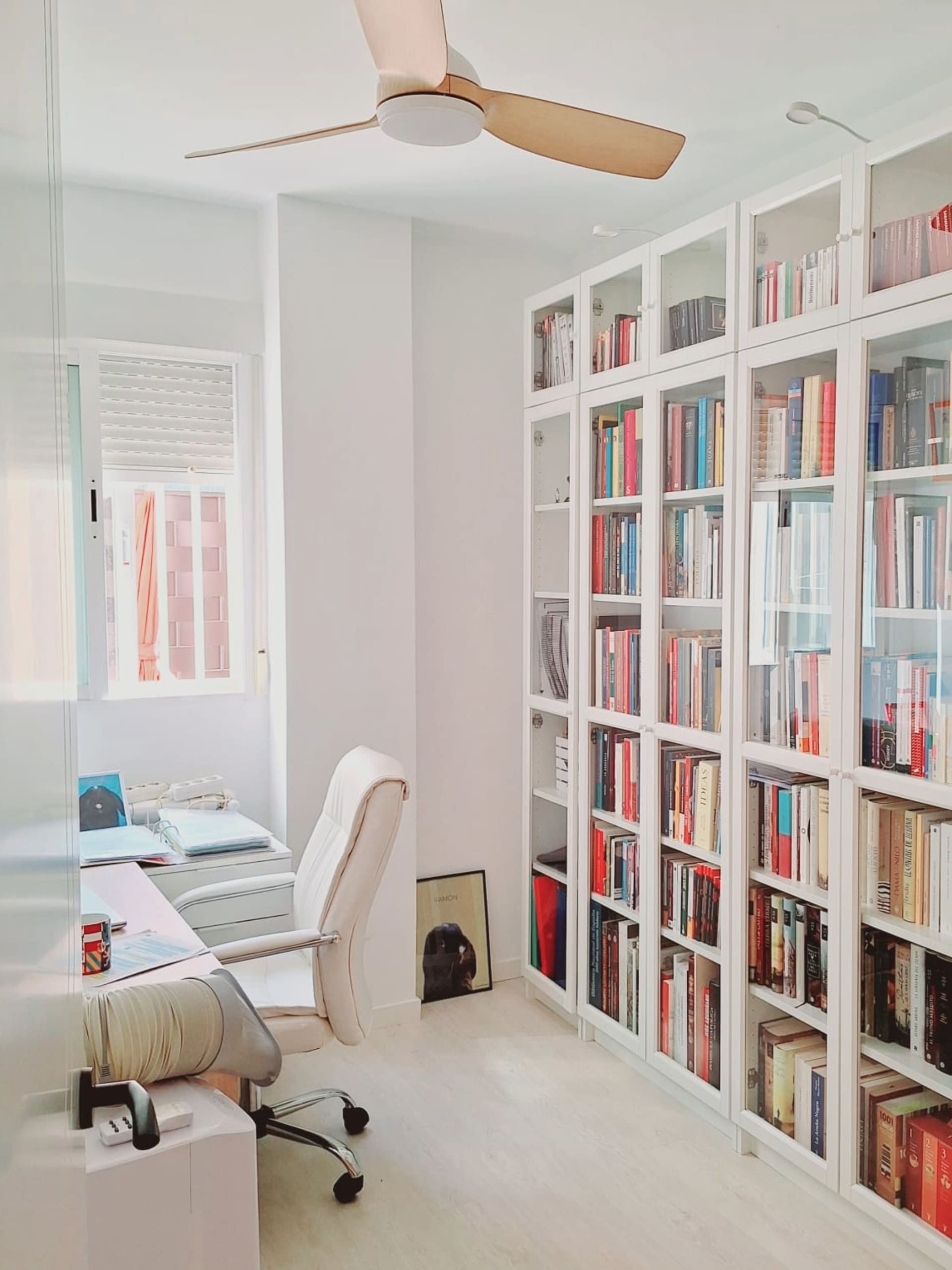 Una habitación con muchas estanterías y un ventilador de techo.