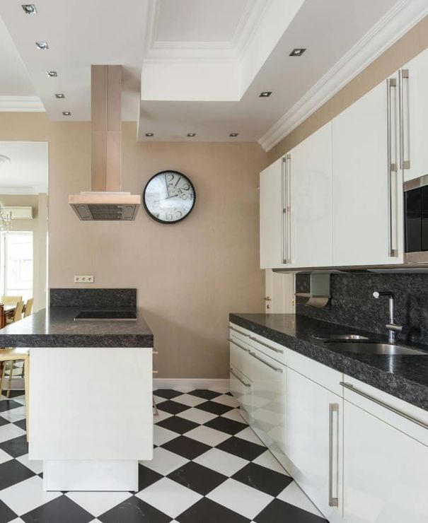 Una cocina con pisos a cuadros blancos y negros y gabinetes blancos.