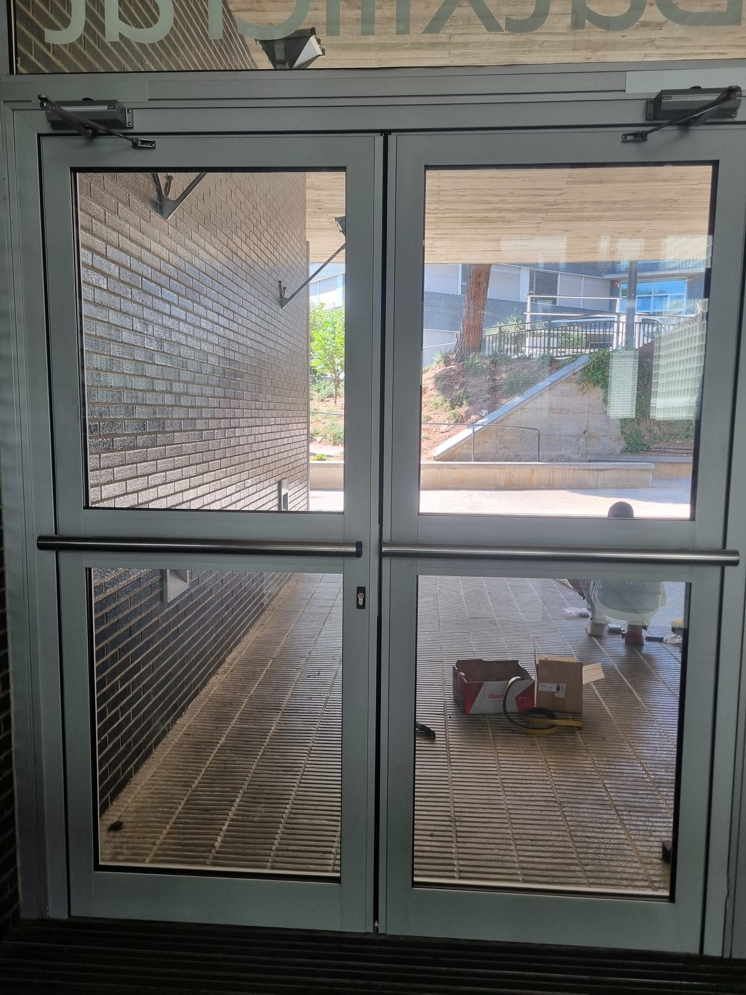 Puertas dobles de cristal con barras horizontales, que dan al exterior.