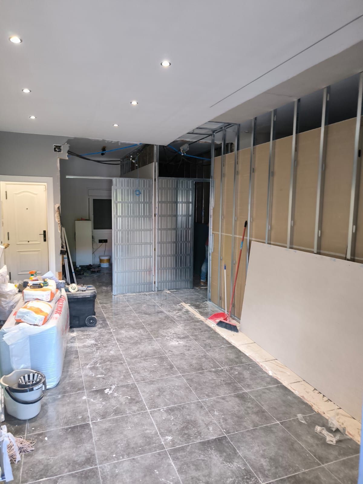 Interior en construcción, con montantes metálicos, paneles de yeso y piso de baldosas.