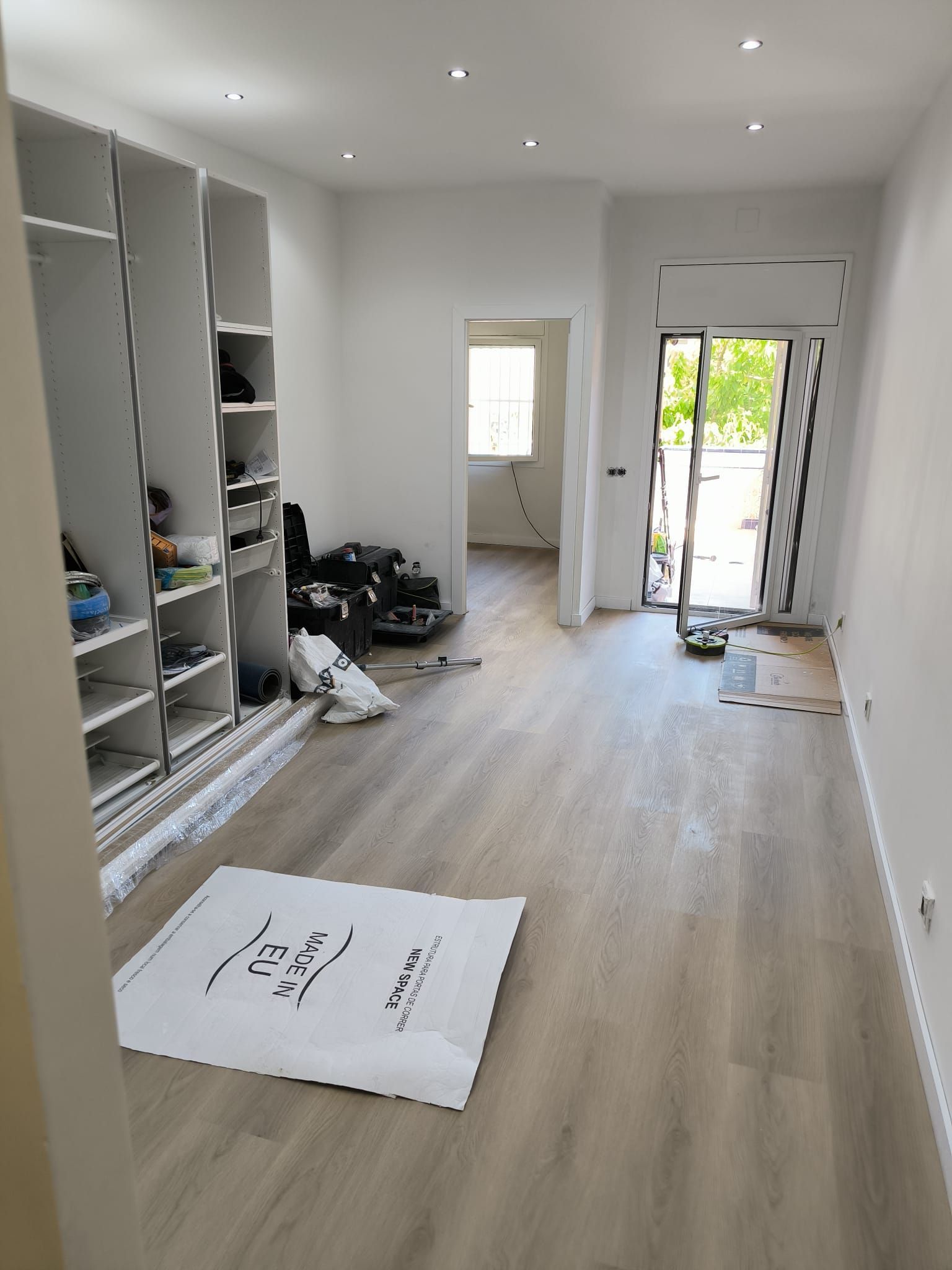 Renovación de habitación interior en progreso con gabinetes instalados, pisos nuevos y puertas abiertas.