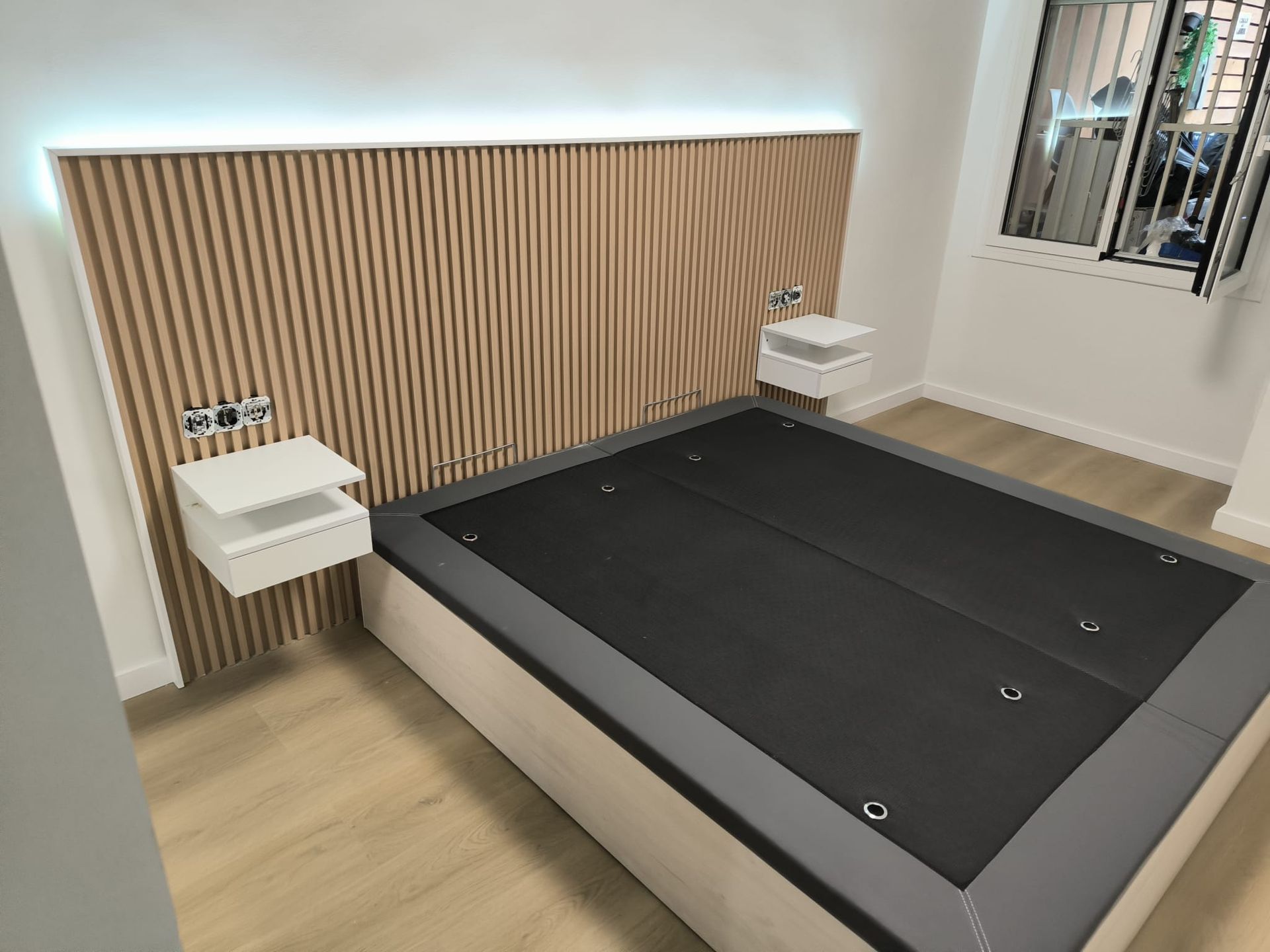 Dormitorio con cabecero de madera, mesitas de noche flotantes y cama plataforma.