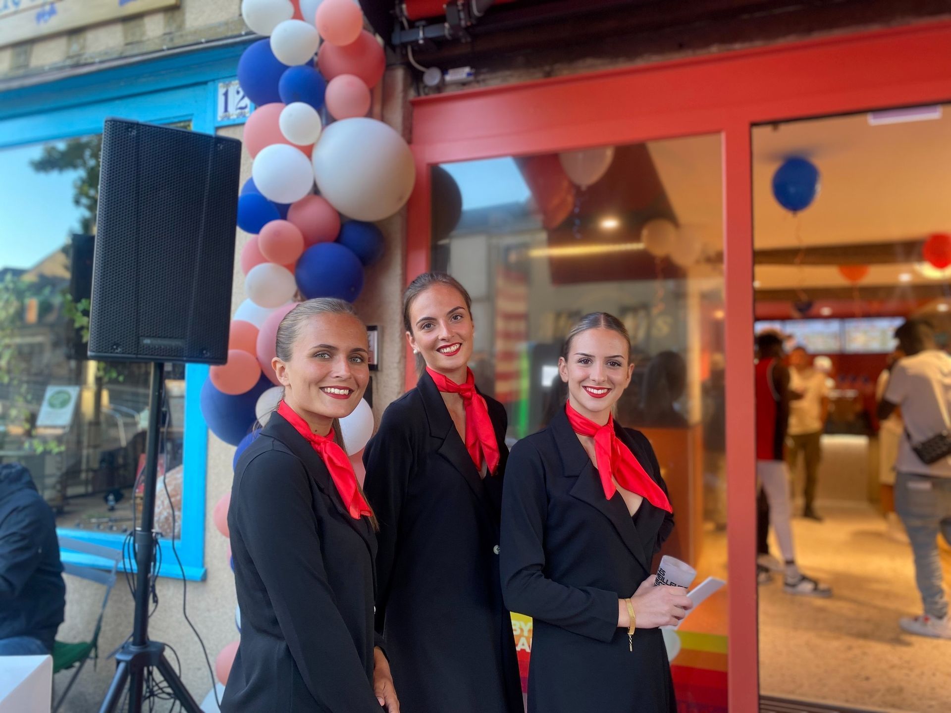 Trois femmes habillées en veste noire et foulard rouge regardant vers le photographe