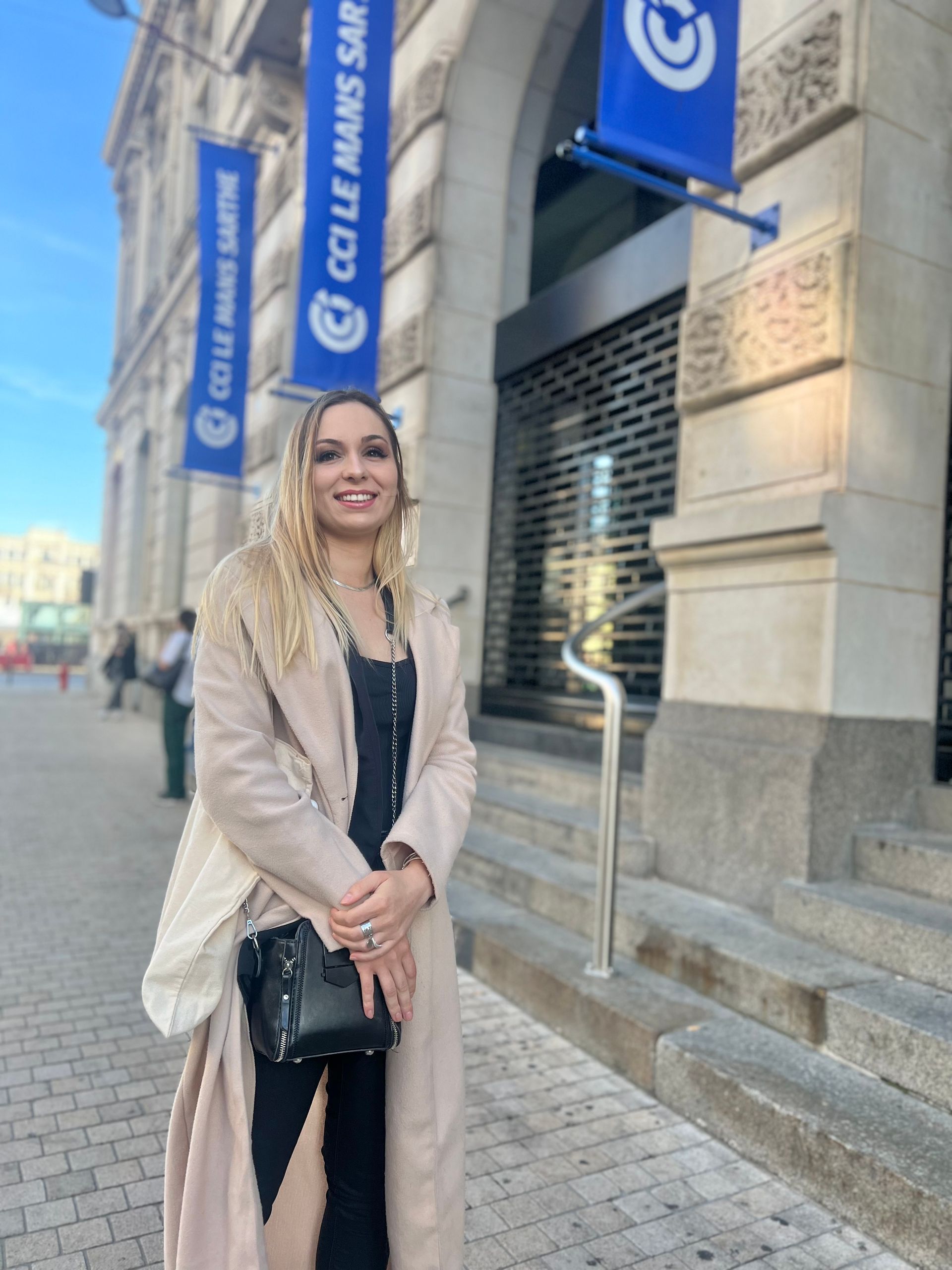 Une femme souriante posant devant les marches de la chambre de commerce et d'industrie