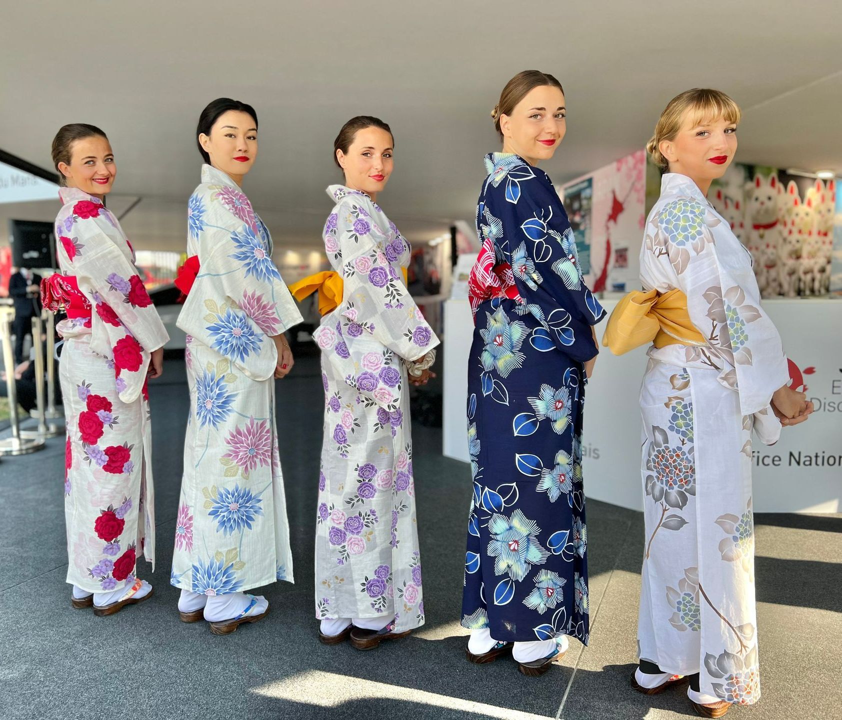 Cinq femmes de dos habillées en kimono regardant vers le photographe