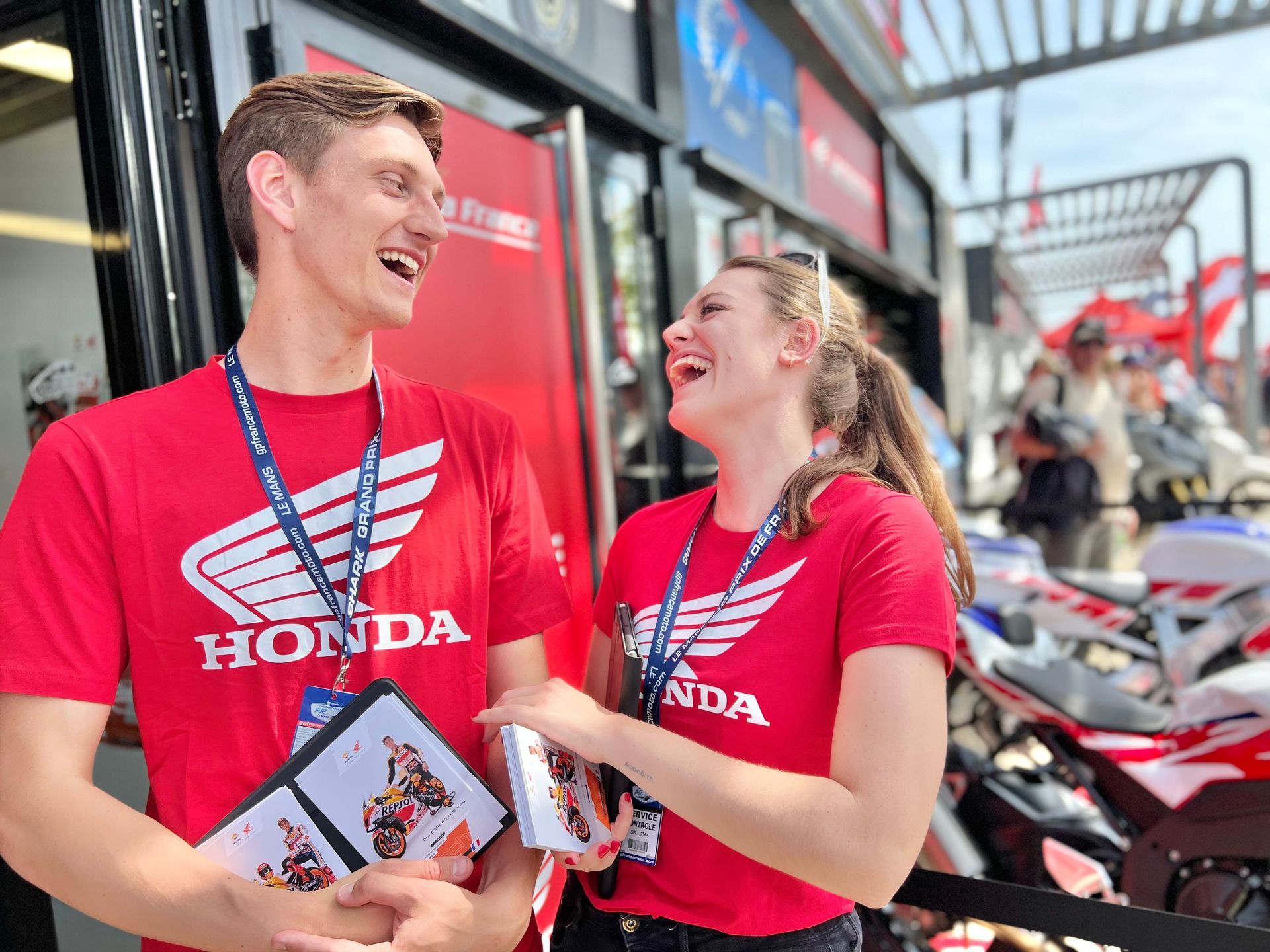 Hôte et hôtesse riant en tenant des flyers