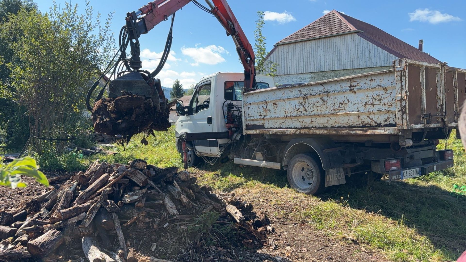 Camion blanc avec pince qui récupère du bois
