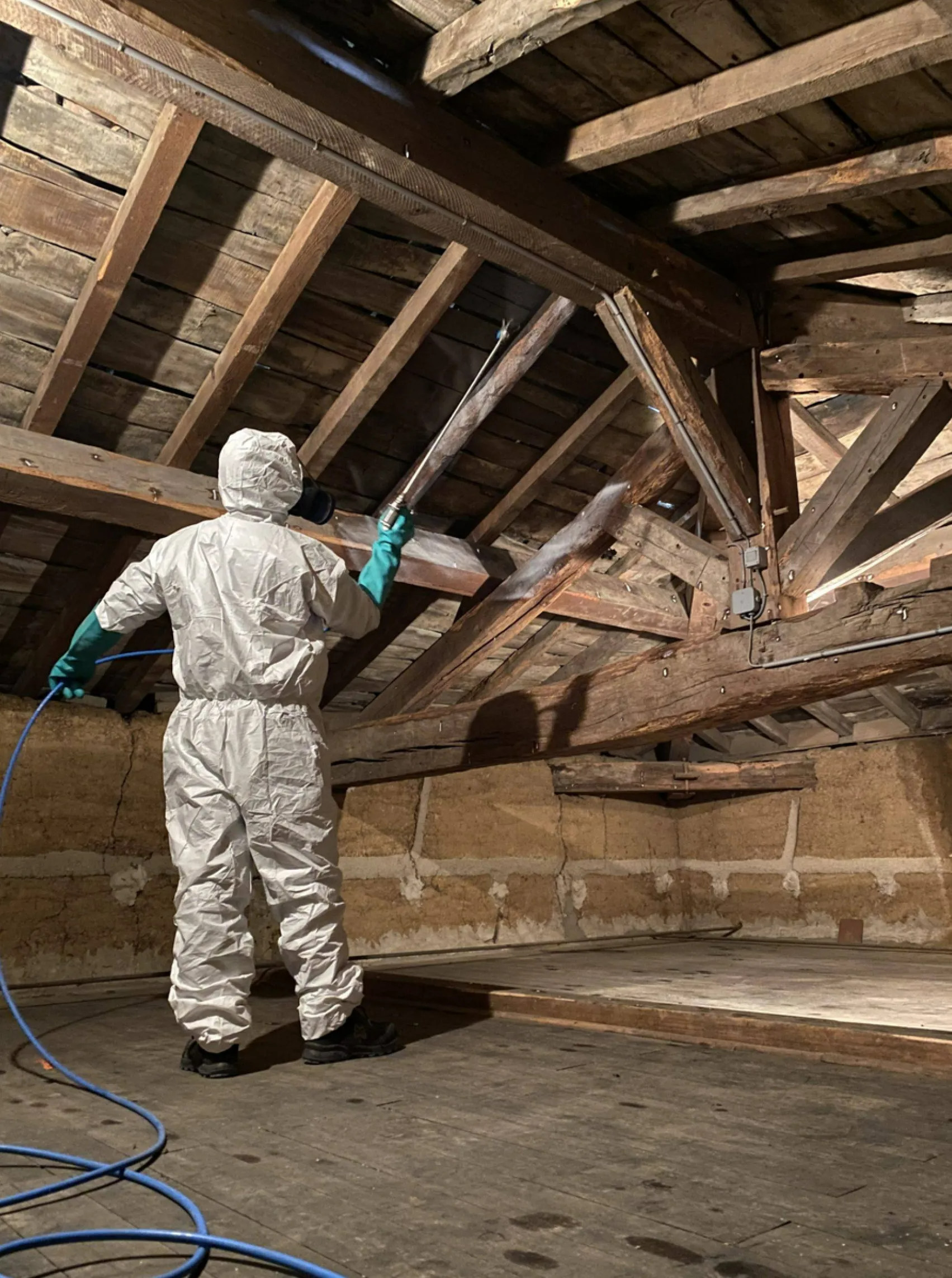 Un ouvrier en tenue de protection qui traite une charpente