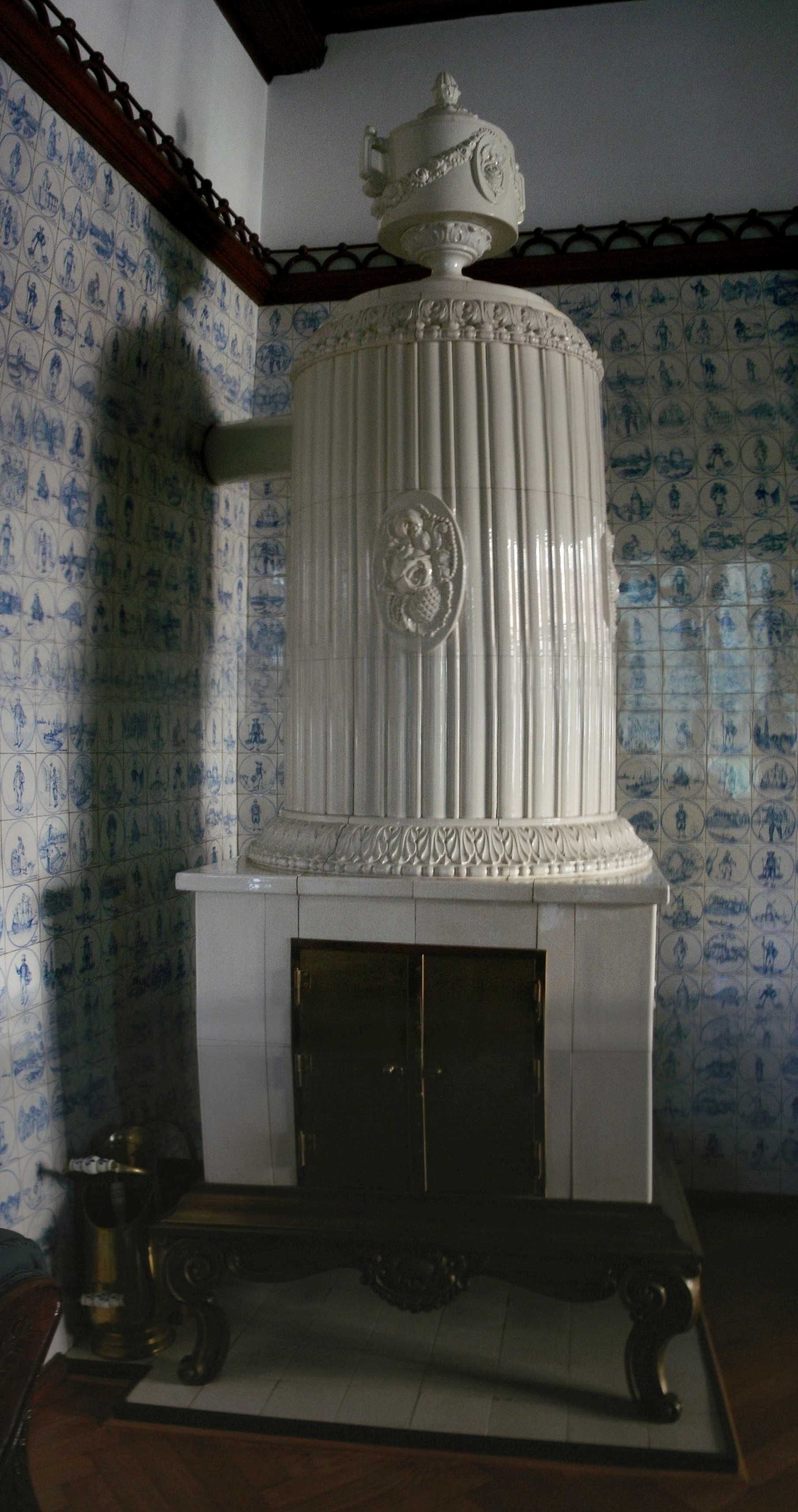 Ein weißer Kamin in einem Raum mit blauen und weißen Fliesen an den Wänden.