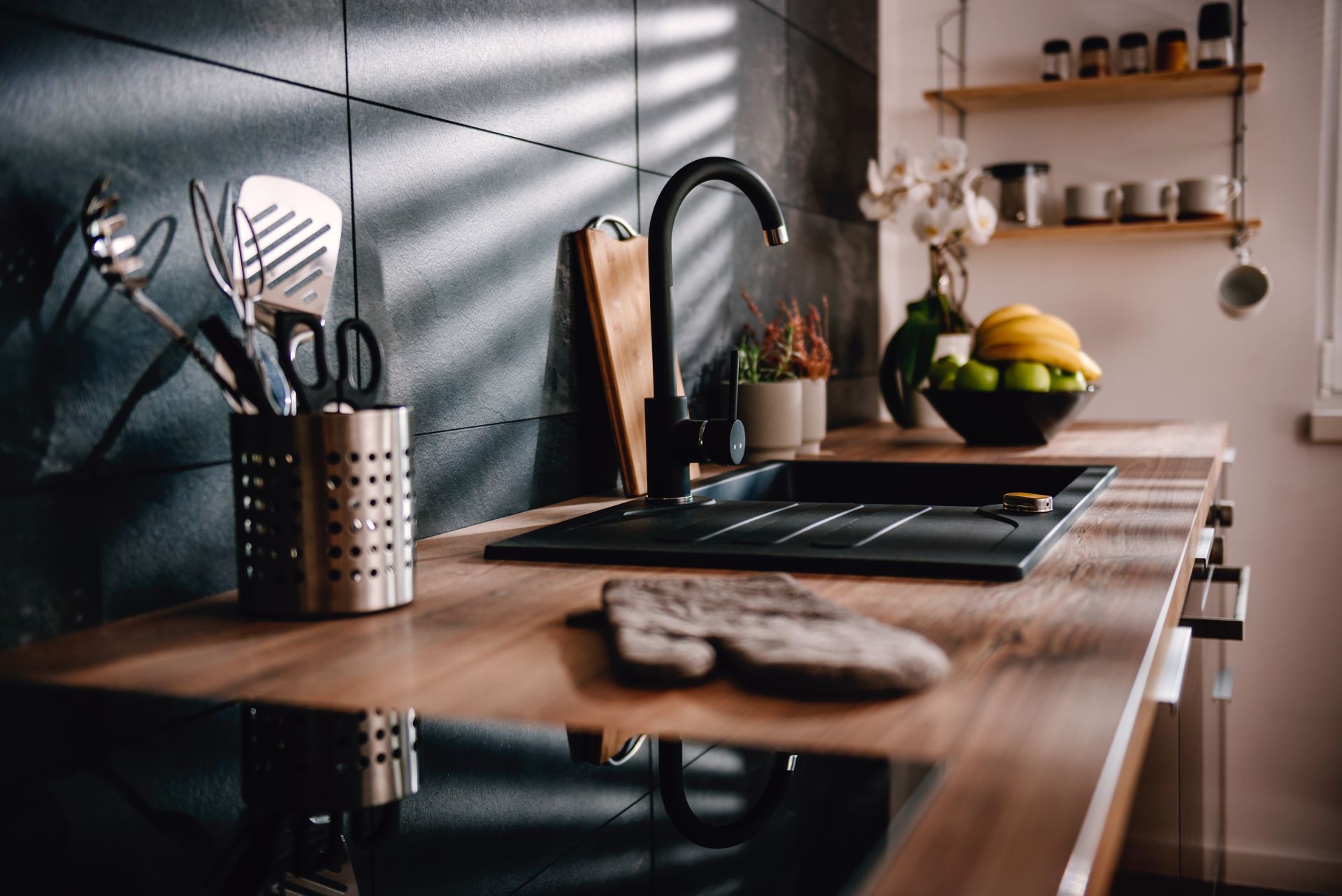 Eine moderne Küche mit Spüle, Herd und Backofen und Küchenutensilien auf der Holz-Arbeitsfläche.
