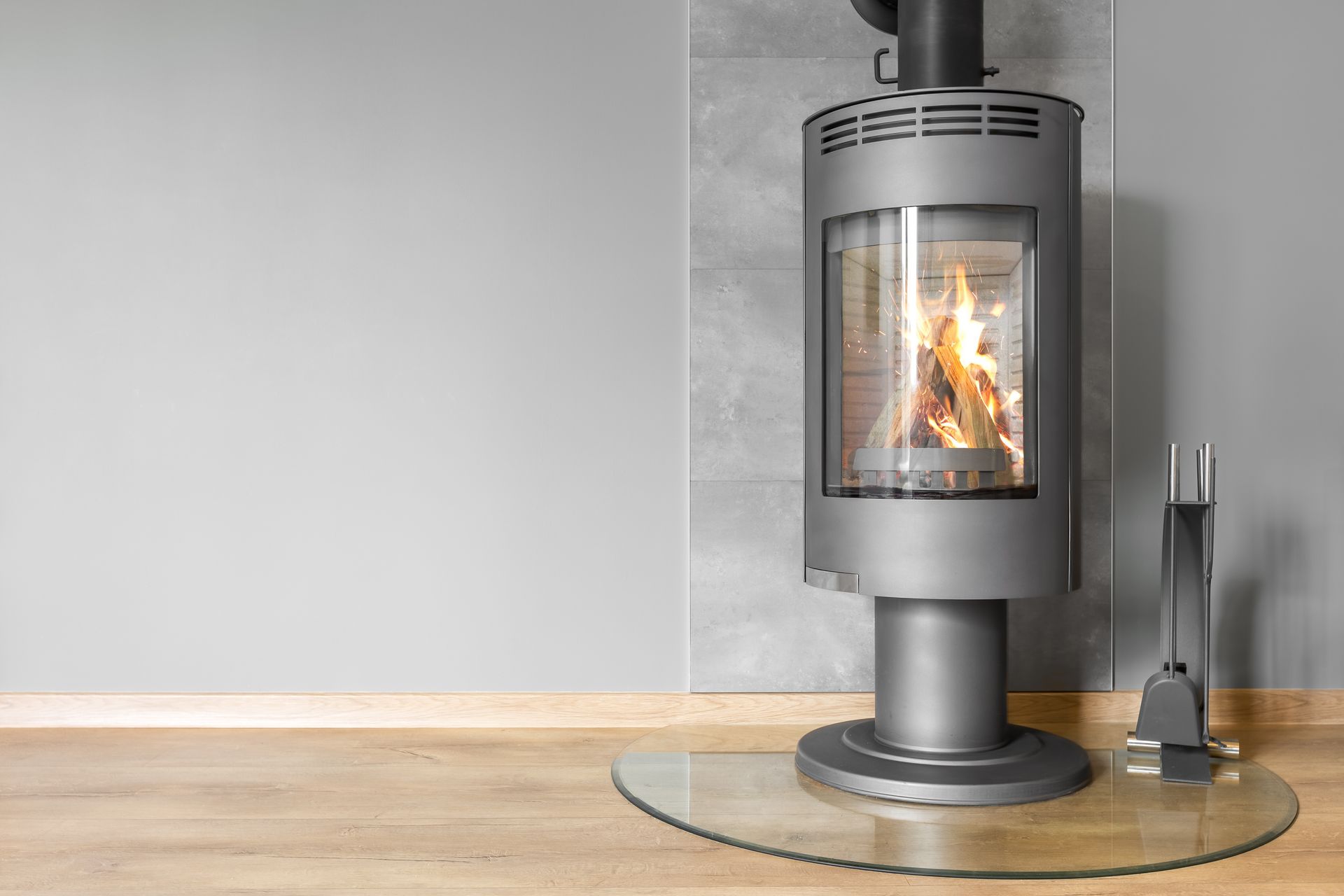 In einem Wohnzimmer steht auf einem Holzboden ein silberner Kamin