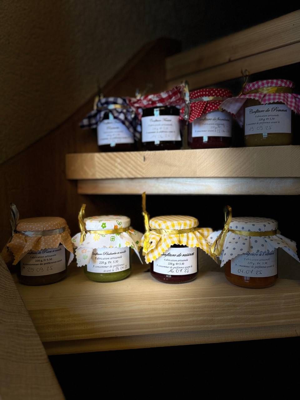 Des pots de confiture sont alignés sur une étagère en bois