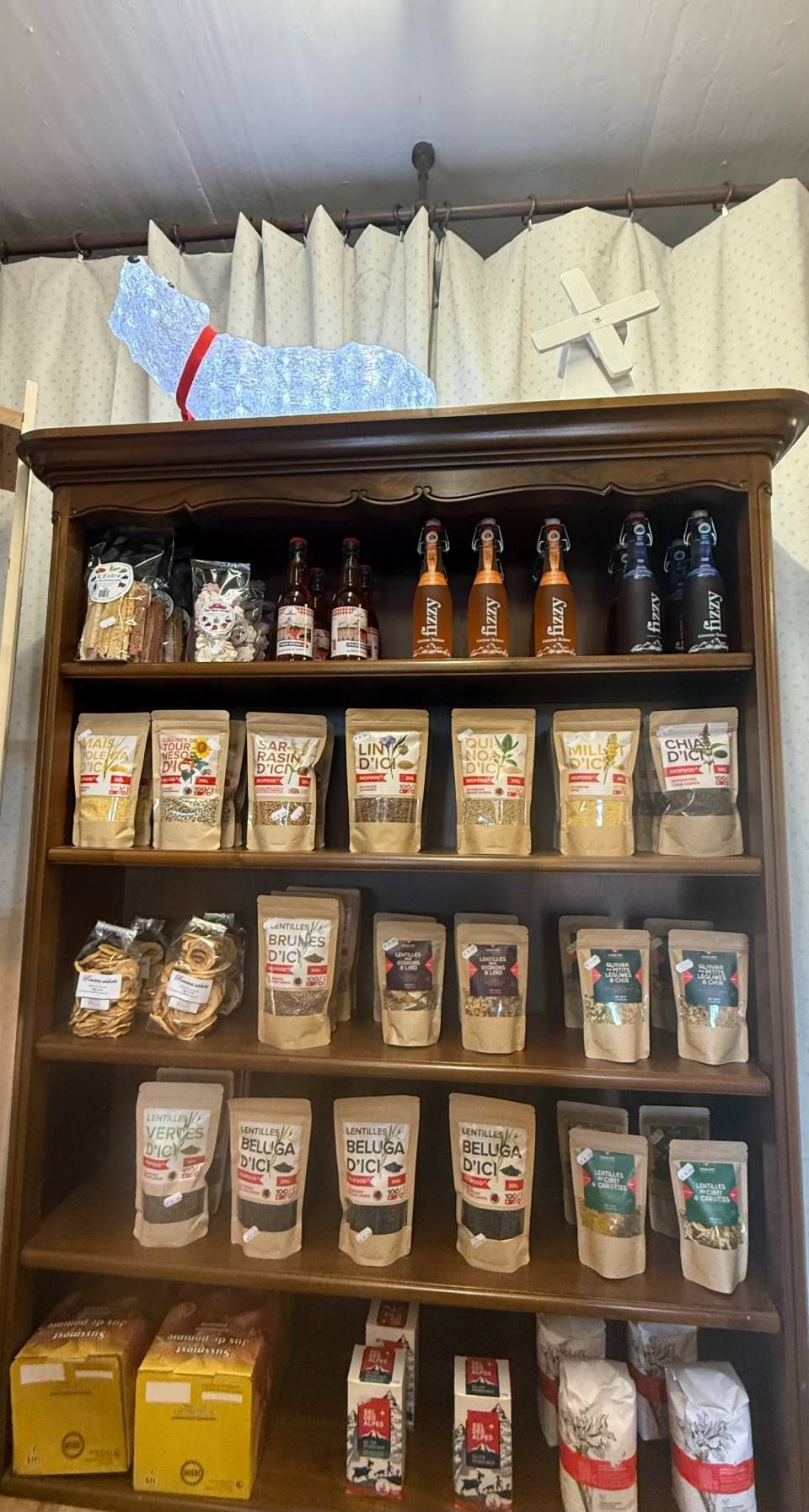 Une étagère en bois remplie de sacs de nourriture et de bouteilles.