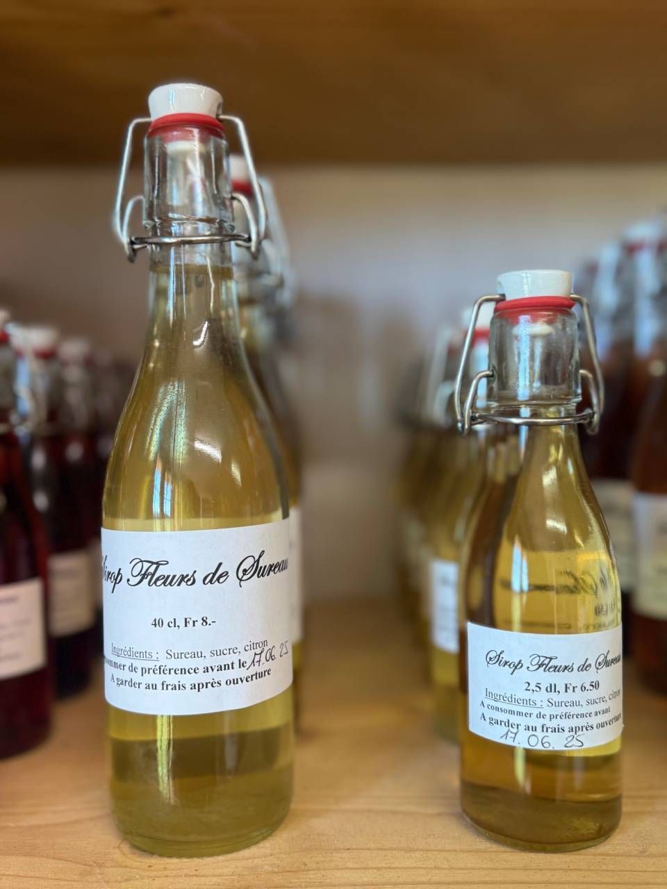 Deux bouteilles de sirop sont posées sur une étagère en bois.