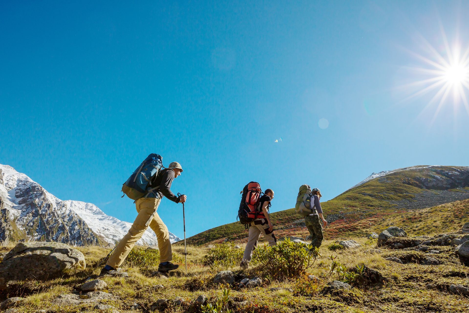 Un grupo de personas con mochilas están caminando por una montaña.