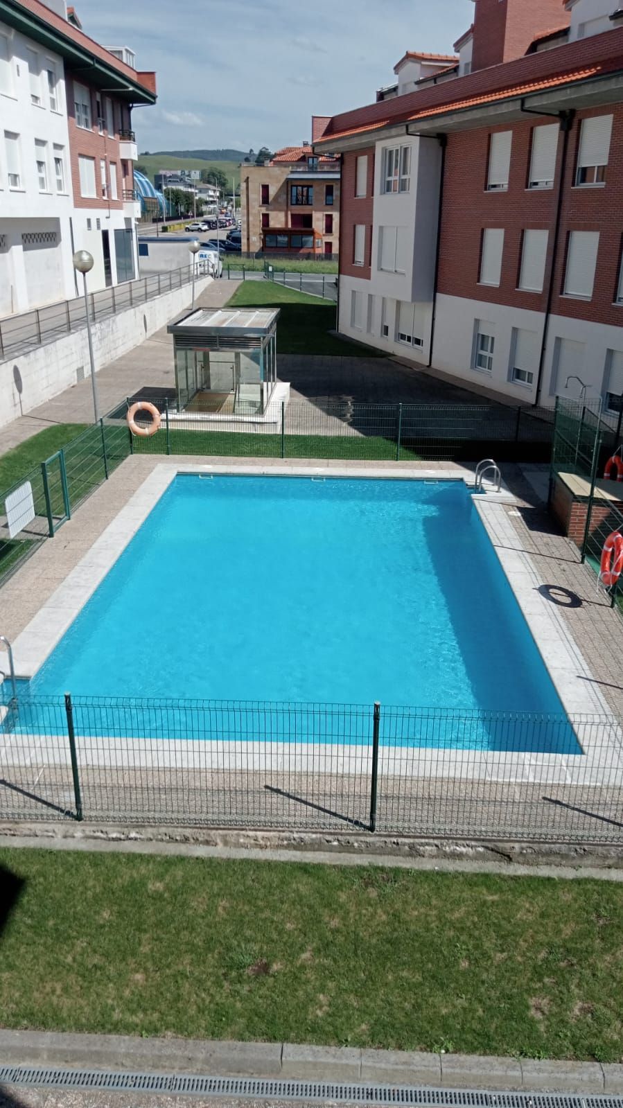 Una gran piscina está rodeada por una valla delante de un edificio.
