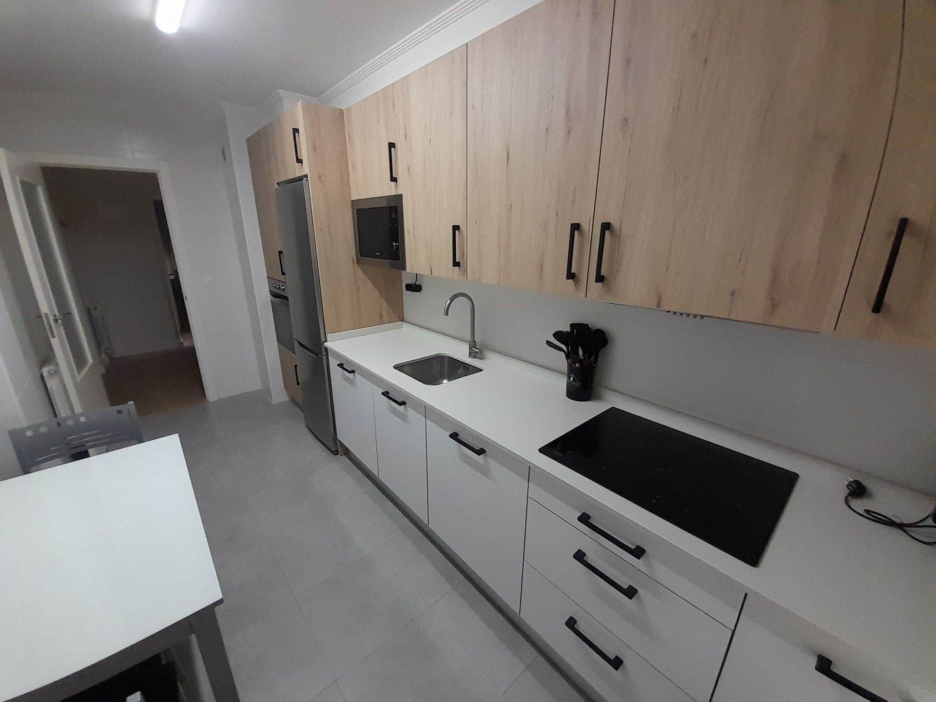 Una cocina con gabinetes de madera y encimeras blancas.