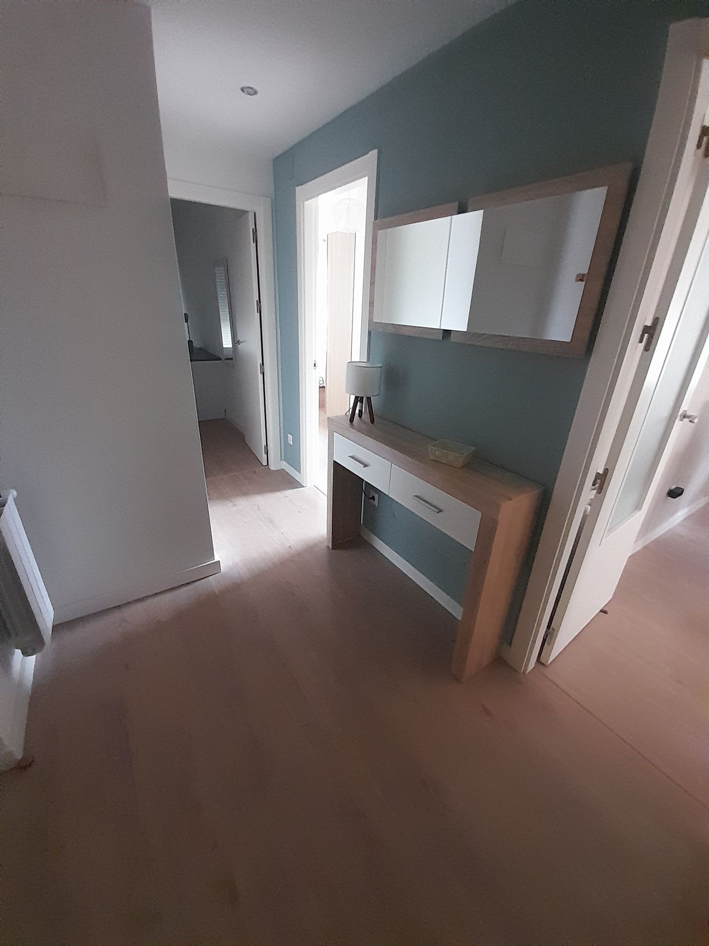 Un pasillo con un escritorio y un espejo en la pared.