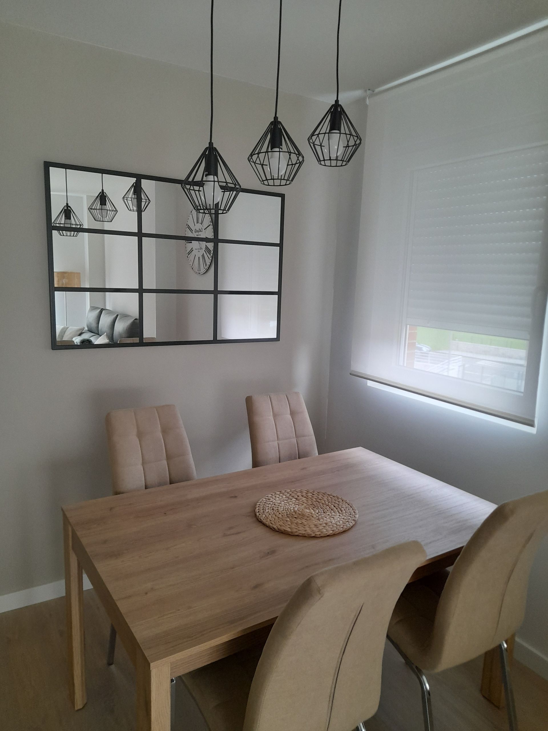 Un comedor con una mesa y sillas y un espejo en la pared.