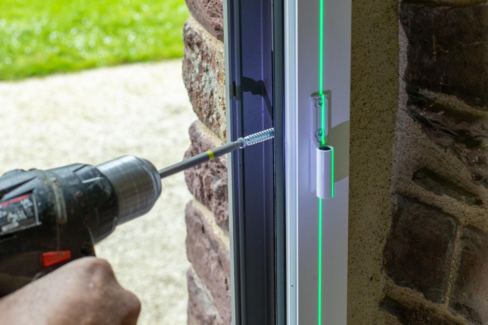 Homme qui visse un encadrement de porte.