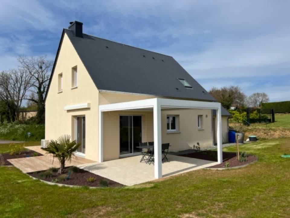 Maison beige avec un toit noir, une couverture de patio blanche et une cour paysagée.