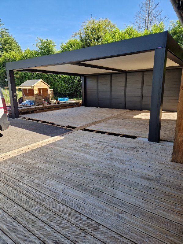 Pergola avec cadre gris, sol gris clair et terrasse en bois en extérieur.