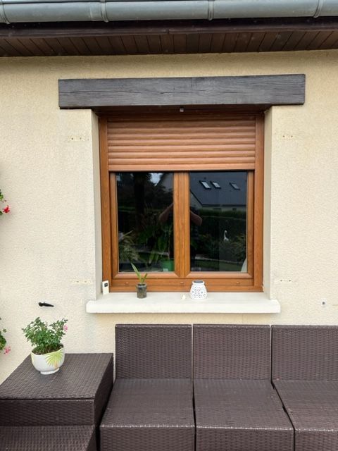 Fenêtre avec volets marron et cadre en bois, au-dessus d'un coin salon de patio.