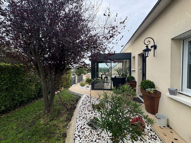 Maison avec une véranda côté jardin.