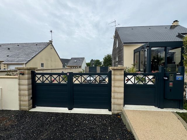 Portail bleu foncé avec dessus décoratif devant les maisons à deux étages.