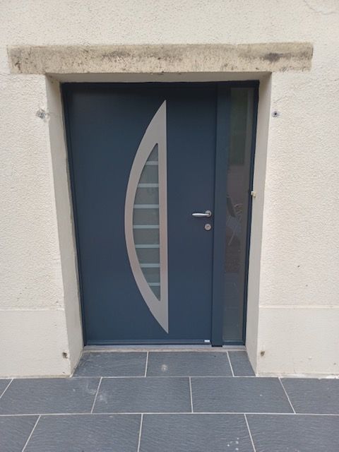 Porte d'entrée bleue avec accent argenté et fenêtre latérale dans l'embrasure de la porte blanche.