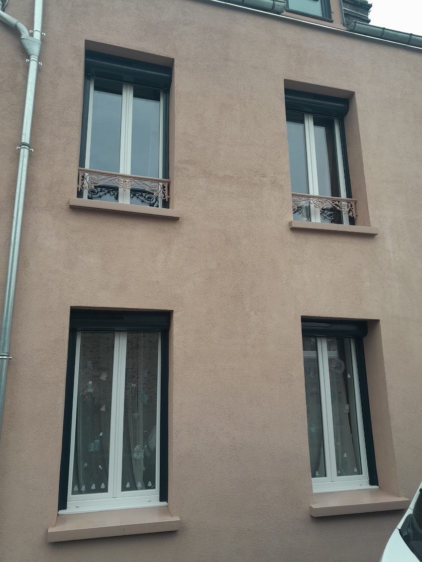 Un bâtiment avec quatre fenêtres ; extérieur peint en brun clair.