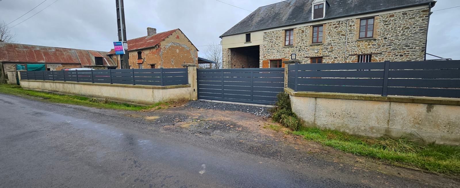 Une route grise menant à une porte devant un bâtiment en pierre sous un ciel couvert.