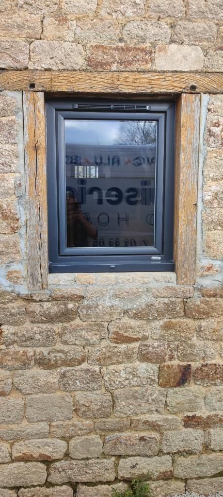 Fenêtre gris foncé sur une maison en pierre.