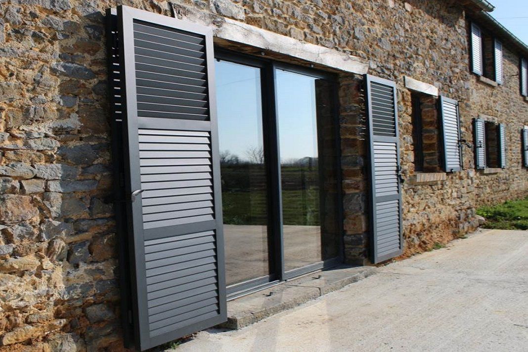 Volets battants de type persiennes sur une façade de maison.