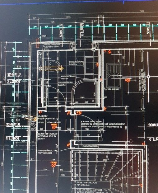 Zwei Personen an Tisch, Laptop und Baupläne