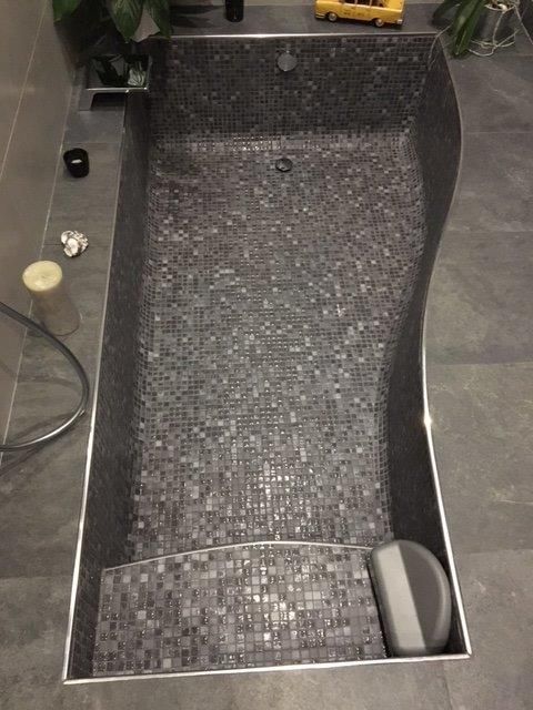 Rampe de mini-golf carrelée de noir avec un canal incliné et une petite balle blanche en bas à droite