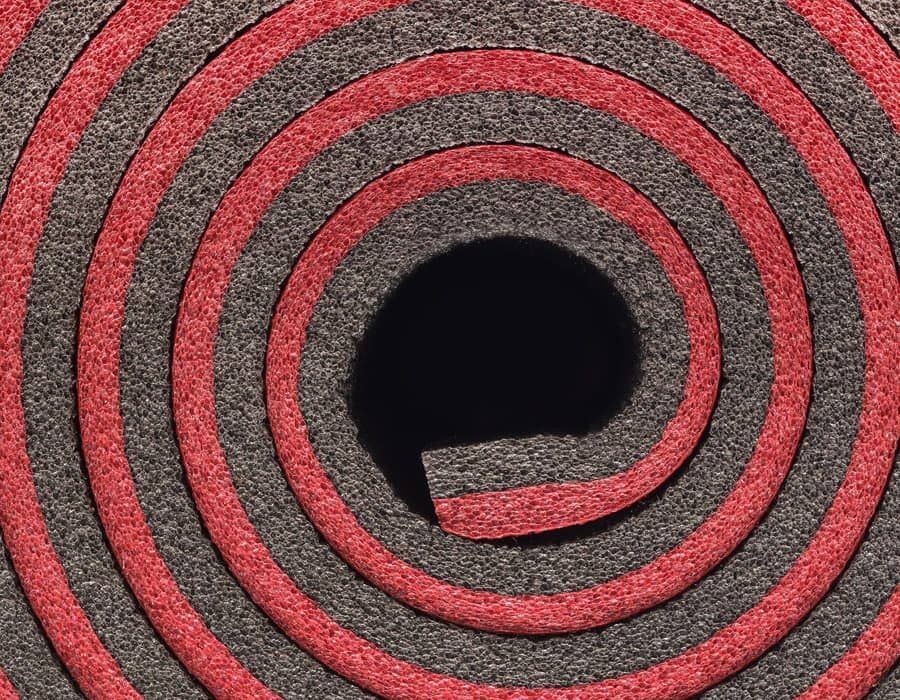 Tapis en spirale rouge et gris avec une ouverture ou un trou central foncé.