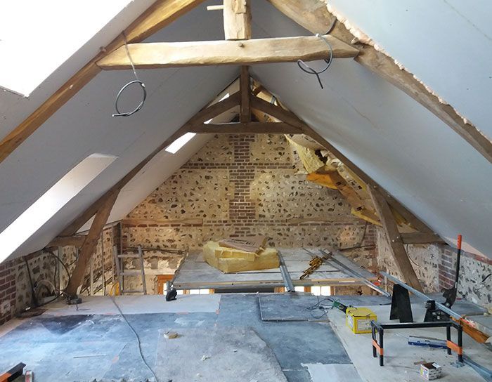 Rénovation des combles avec charpente apparente, isolation et outils de construction au sol