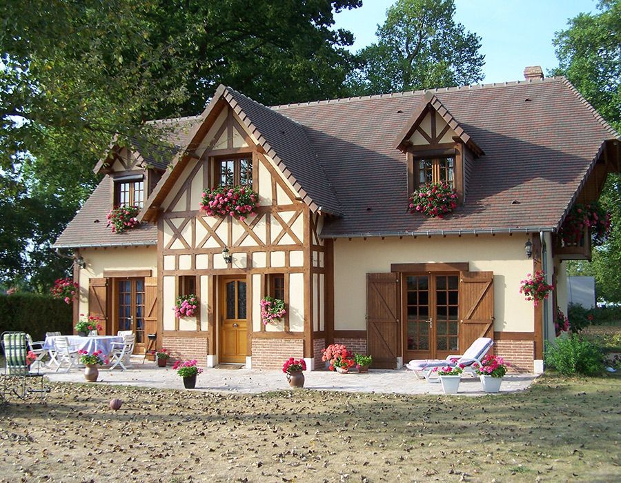 Charmant cottage avec jardinières, boiseries et chaises de patio dans un jardin ensoleillé