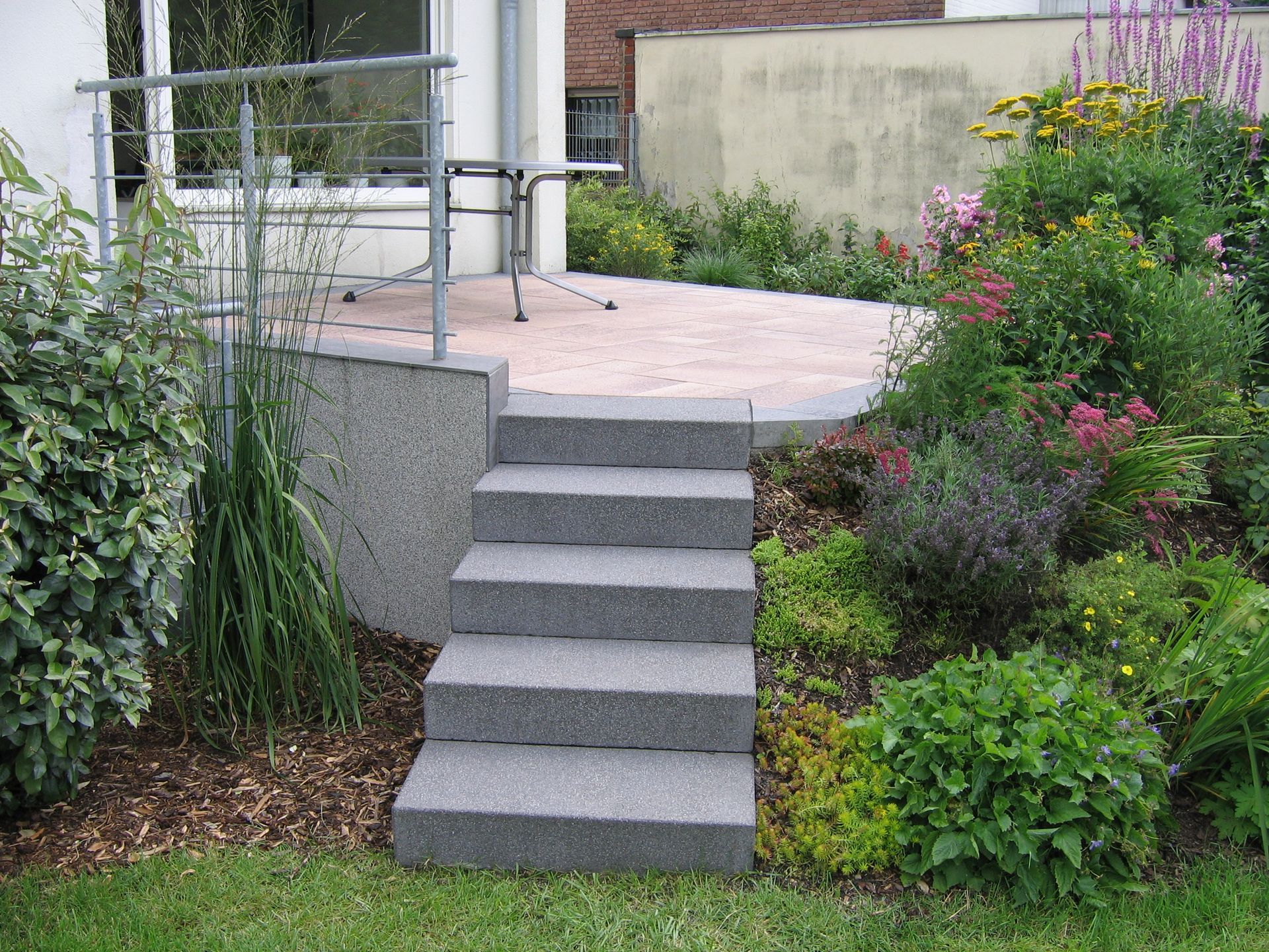 Stufen führen zu einer von einem Garten umgebenen Terrasse.