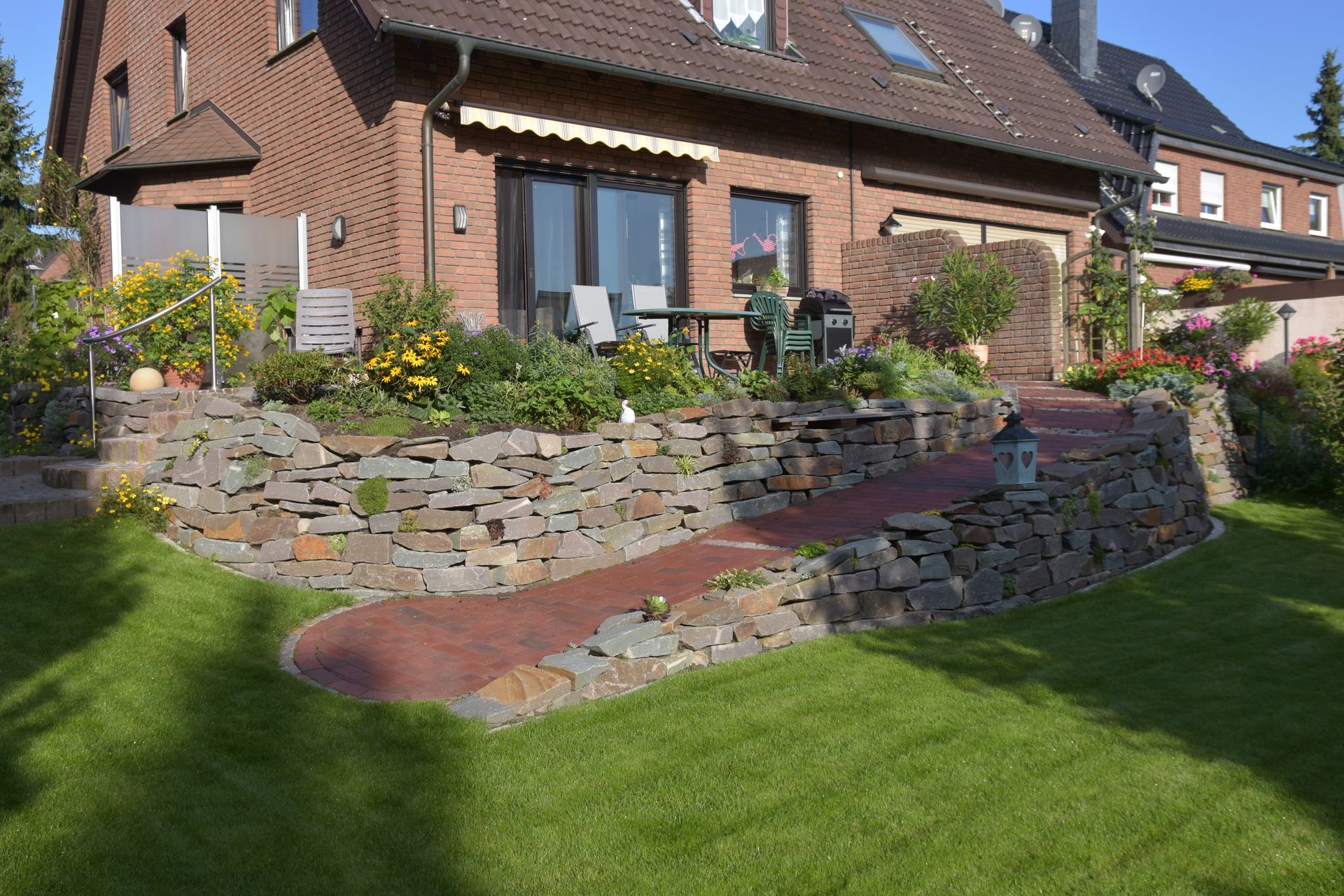 Backsteinhaus mit einem von Steinmauern umgebenen Garten mit einem roten Backsteinweg und einem üppigen grünen Rasen.