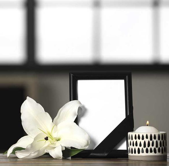 Un marco de fotos con una flor blanca y una vela sobre una mesa.