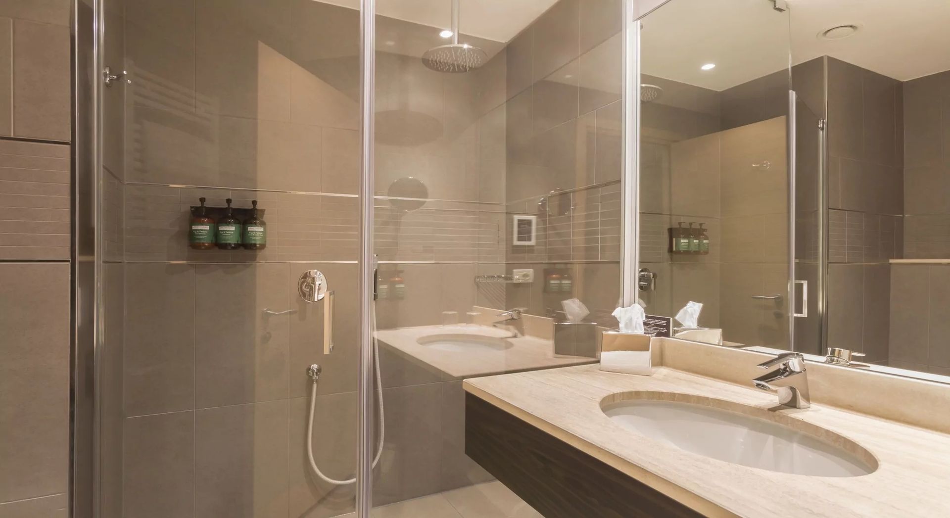 Salle de bains moderne beige avec douche en verre, double vasque et grand miroir mural